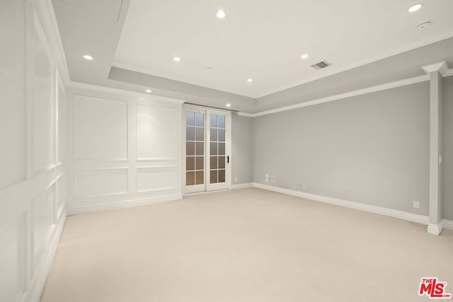 carpeted spare room featuring a raised ceiling, crown molding, and french doors