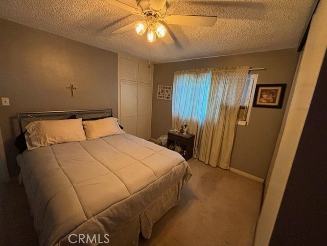 carpeted bedroom with ceiling fan and a textured ceiling