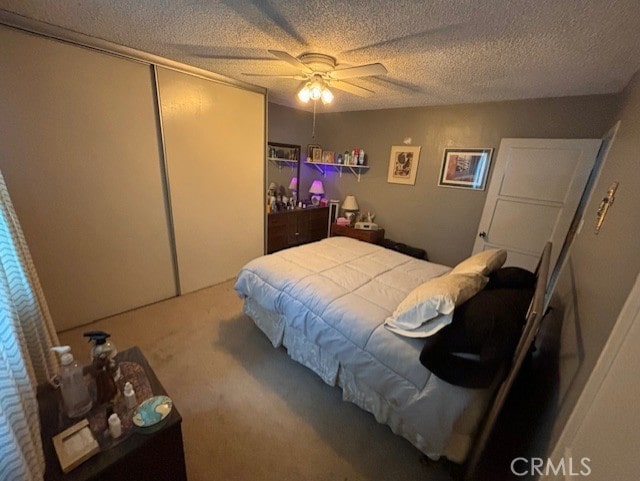 carpeted bedroom with ceiling fan, a textured ceiling, and a closet