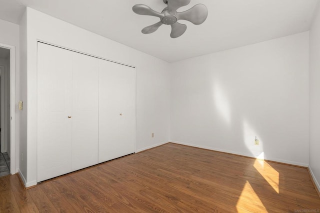 unfurnished bedroom featuring ceiling fan, a closet, and hardwood / wood-style flooring