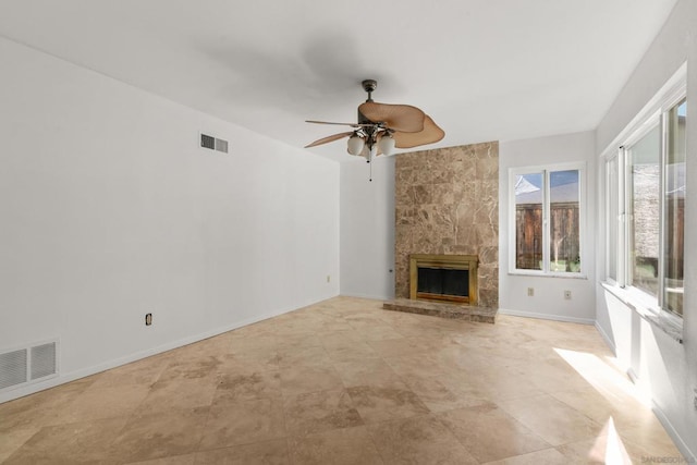 unfurnished living room with ceiling fan and a large fireplace