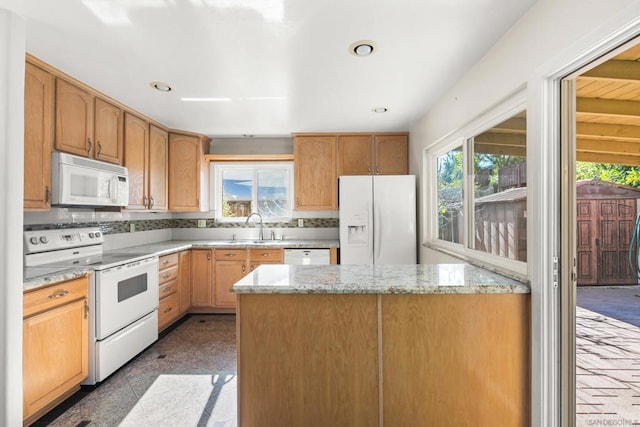 kitchen with backsplash, a kitchen island, sink, white appliances, and light stone counters