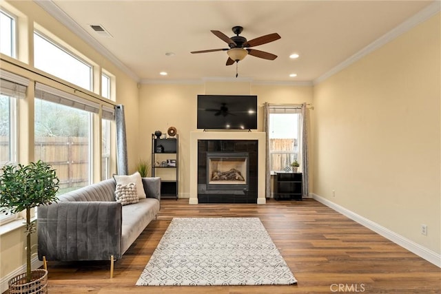 living room with plenty of natural light, crown molding, a fireplace, and hardwood / wood-style floors