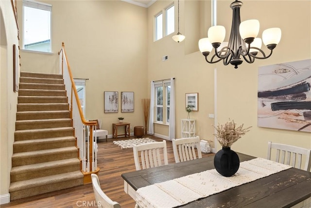 dining area featuring a towering ceiling, a chandelier, and hardwood / wood-style flooring