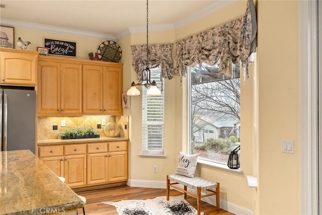 kitchen with tasteful backsplash, crown molding, hanging light fixtures, light brown cabinetry, and stainless steel fridge