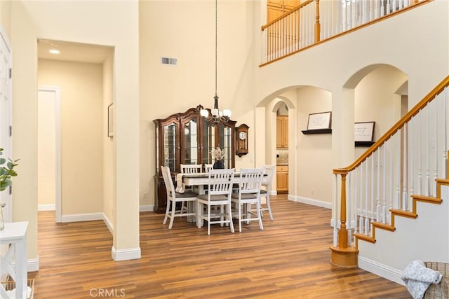 dining space featuring an inviting chandelier, wood-type flooring, and a high ceiling