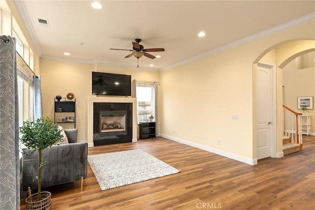 living room with ceiling fan, crown molding, a fireplace, and hardwood / wood-style floors