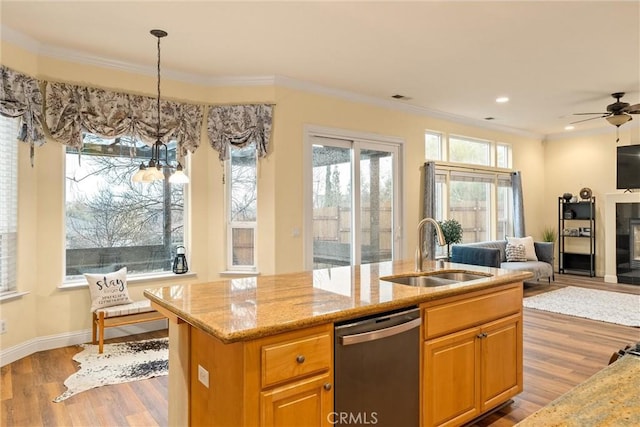 kitchen with a kitchen island with sink, light wood-type flooring, dishwasher, light stone countertops, and sink