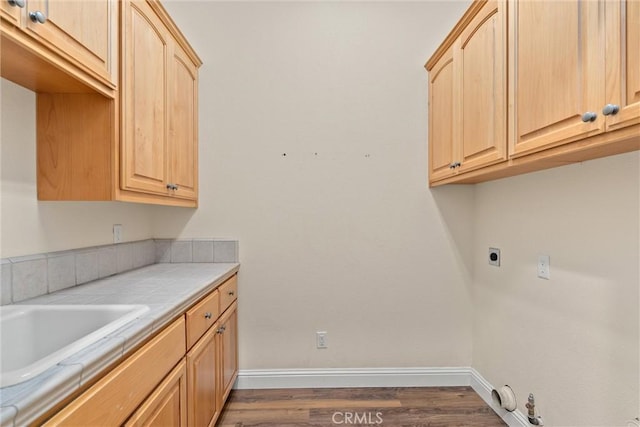 washroom with cabinets, electric dryer hookup, sink, dark hardwood / wood-style floors, and gas dryer hookup