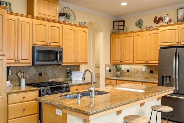 kitchen with a center island with sink, a breakfast bar area, appliances with stainless steel finishes, tasteful backsplash, and light stone counters