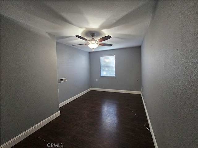 empty room featuring dark wood-type flooring and ceiling fan