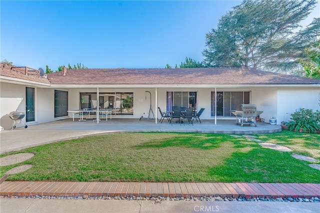 rear view of house featuring a lawn and a patio area