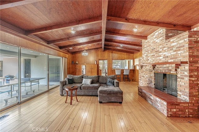 living room featuring wooden ceiling, lofted ceiling with beams, wooden walls, a brick fireplace, and light wood-type flooring