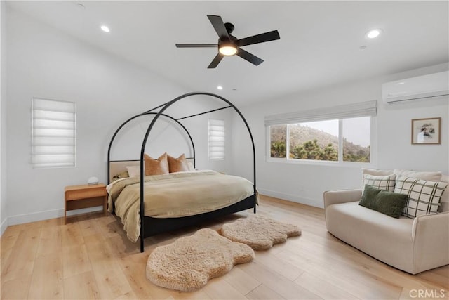 bedroom featuring ceiling fan, a wall mounted AC, and light hardwood / wood-style floors