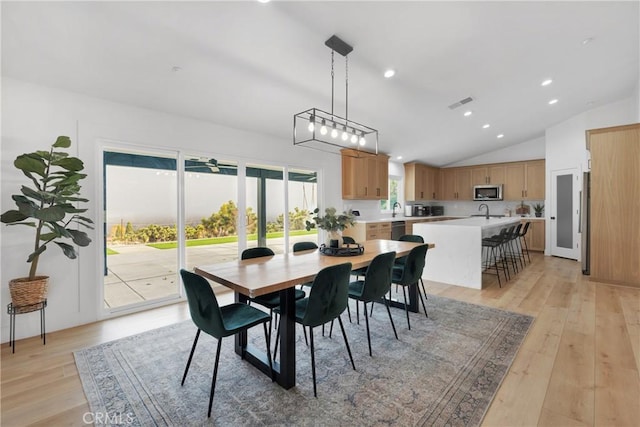 dining area featuring vaulted ceiling, ceiling fan, light wood-type flooring, and sink