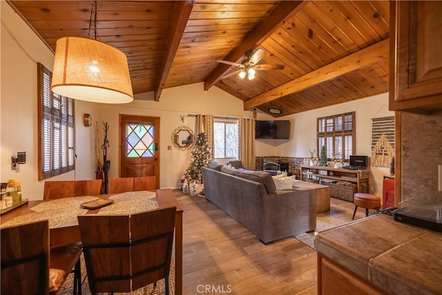 living room featuring ceiling fan, lofted ceiling with beams, wood ceiling, and light hardwood / wood-style flooring