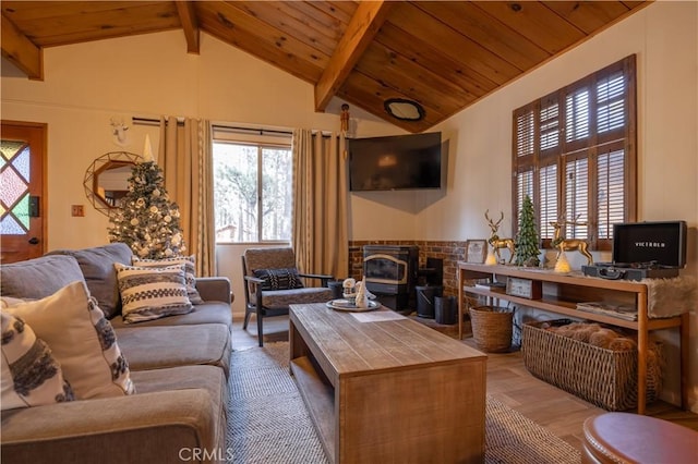 living room with vaulted ceiling with beams, wood ceiling, and a wood stove