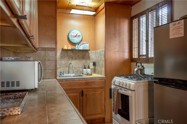 kitchen with stainless steel fridge, sink, and white gas range oven