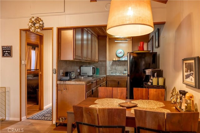 kitchen with black refrigerator, tasteful backsplash, light hardwood / wood-style flooring, and sink