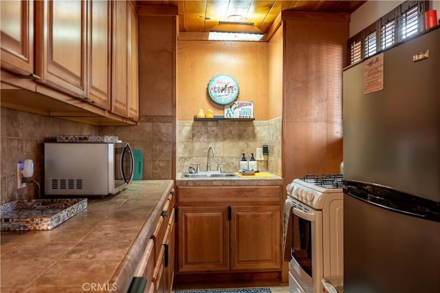 kitchen with tile countertops, sink, and appliances with stainless steel finishes