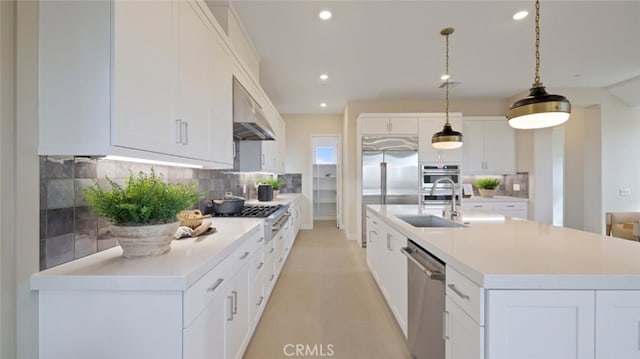 kitchen with pendant lighting, backsplash, a kitchen island with sink, white cabinets, and stainless steel appliances