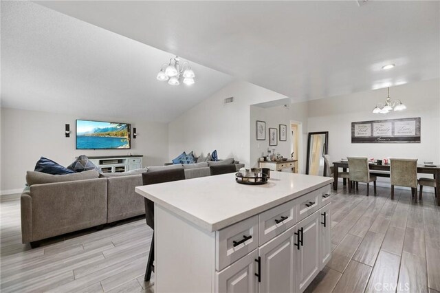 kitchen featuring a kitchen island, decorative light fixtures, light hardwood / wood-style floors, white cabinetry, and a chandelier