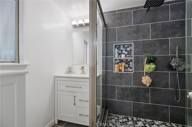 bathroom with tiled shower, vanity, and tile patterned flooring