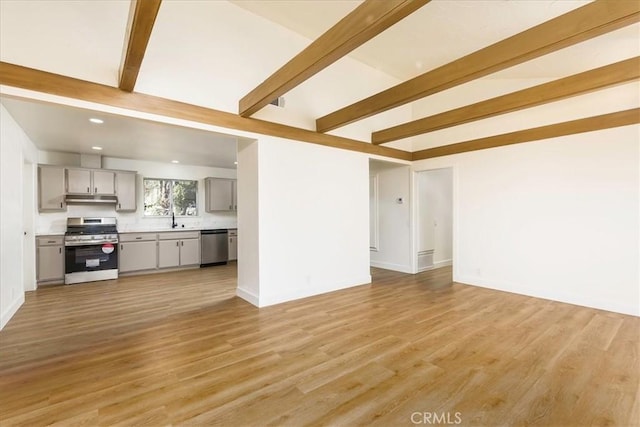 unfurnished living room featuring beamed ceiling, light hardwood / wood-style floors, and sink