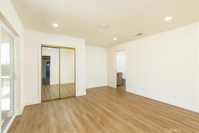 unfurnished bedroom featuring light wood-type flooring, a closet, and connected bathroom