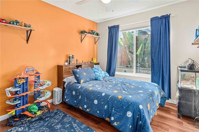 bedroom with ceiling fan, multiple windows, hardwood / wood-style floors, and a textured ceiling