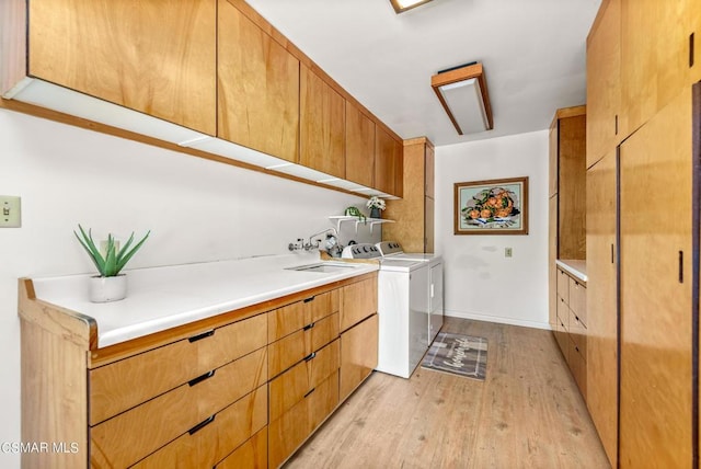 washroom with cabinets, light wood-type flooring, sink, and washing machine and dryer