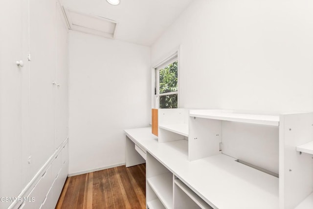 unfurnished office featuring dark hardwood / wood-style floors and built in desk