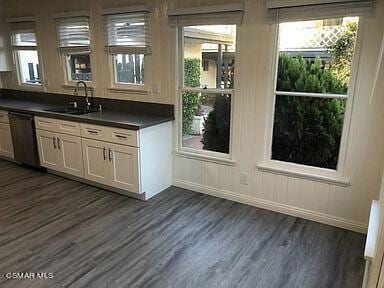 kitchen featuring dishwashing machine, dark hardwood / wood-style floors, white cabinets, and sink