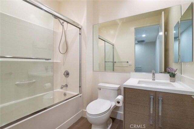 full bathroom with toilet, vanity, hardwood / wood-style floors, and combined bath / shower with glass door