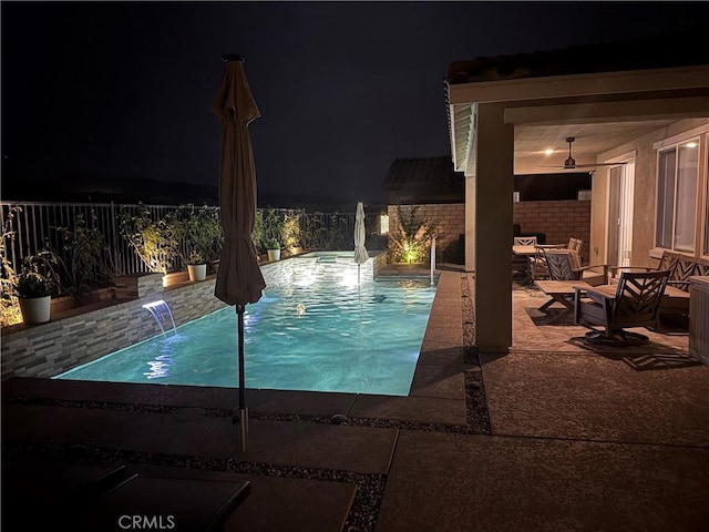 pool at twilight with pool water feature and a patio area