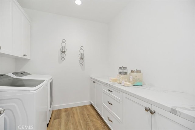 laundry room featuring cabinets, washer and clothes dryer, and light wood-type flooring