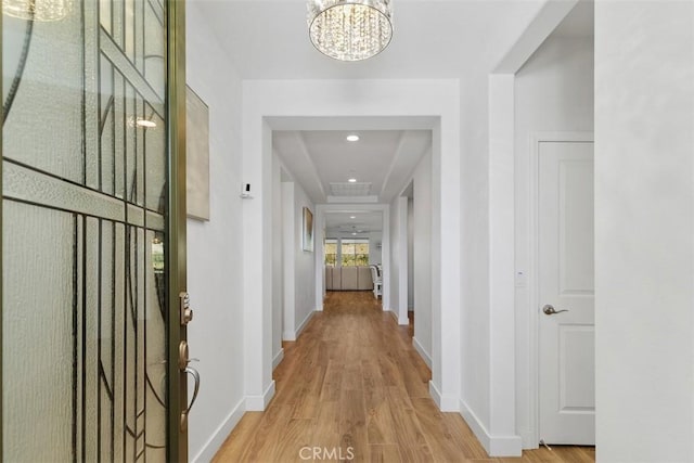 hallway featuring light wood-type flooring and an inviting chandelier