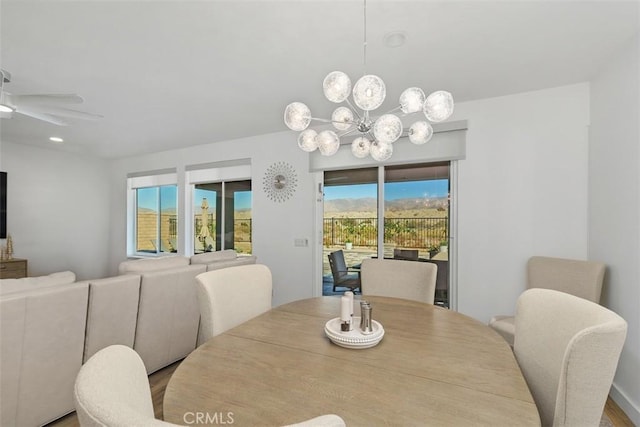 dining space featuring ceiling fan with notable chandelier