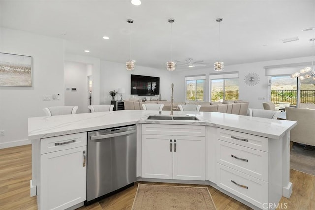 kitchen with white cabinetry, stainless steel dishwasher, sink, and a center island with sink