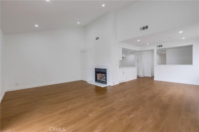 unfurnished living room featuring wood-type flooring and a high ceiling