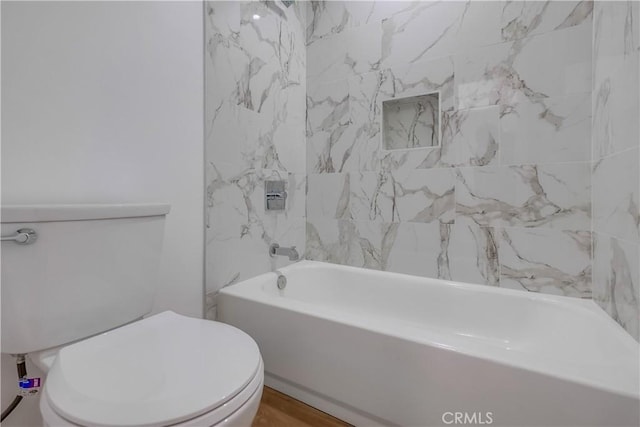 bathroom with tiled shower / bath combo and toilet