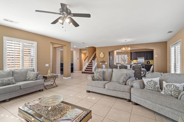 tiled living room featuring ceiling fan with notable chandelier