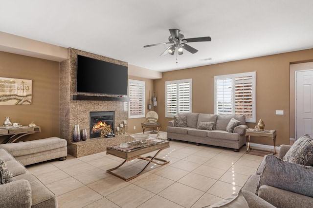 living room featuring ceiling fan, light tile patterned floors, and a fireplace