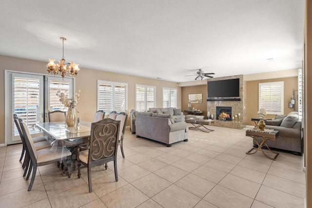 dining room with light tile patterned floors, a healthy amount of sunlight, and ceiling fan with notable chandelier