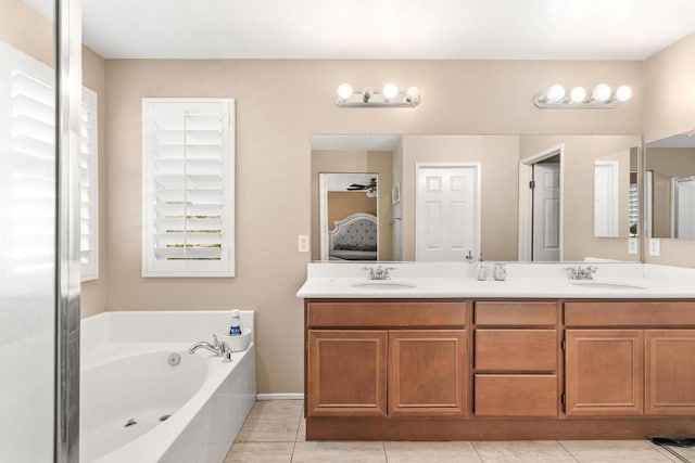 bathroom featuring tile patterned flooring, vanity, and tiled tub