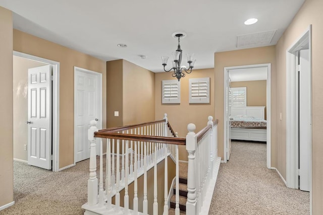 hallway with light carpet and an inviting chandelier