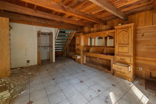 interior space with beamed ceiling, wood walls, wooden ceiling, and light tile patterned floors