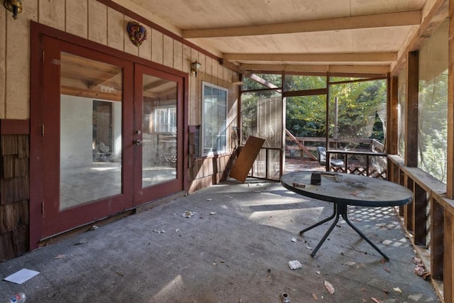 unfurnished sunroom featuring lofted ceiling with beams and a healthy amount of sunlight