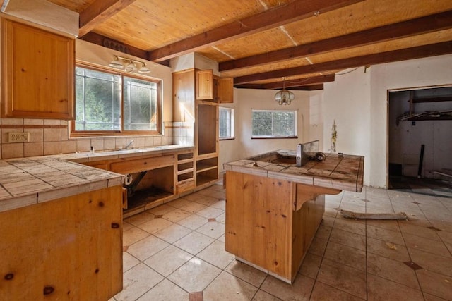 kitchen featuring a wealth of natural light, decorative backsplash, and tile counters