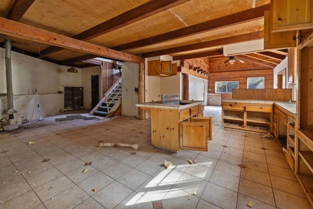 kitchen featuring vaulted ceiling with beams, ceiling fan, tile counters, light tile patterned flooring, and wood ceiling